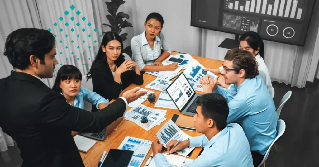 Financial advisor leading a team discussion with charts, reports, and planning documents.